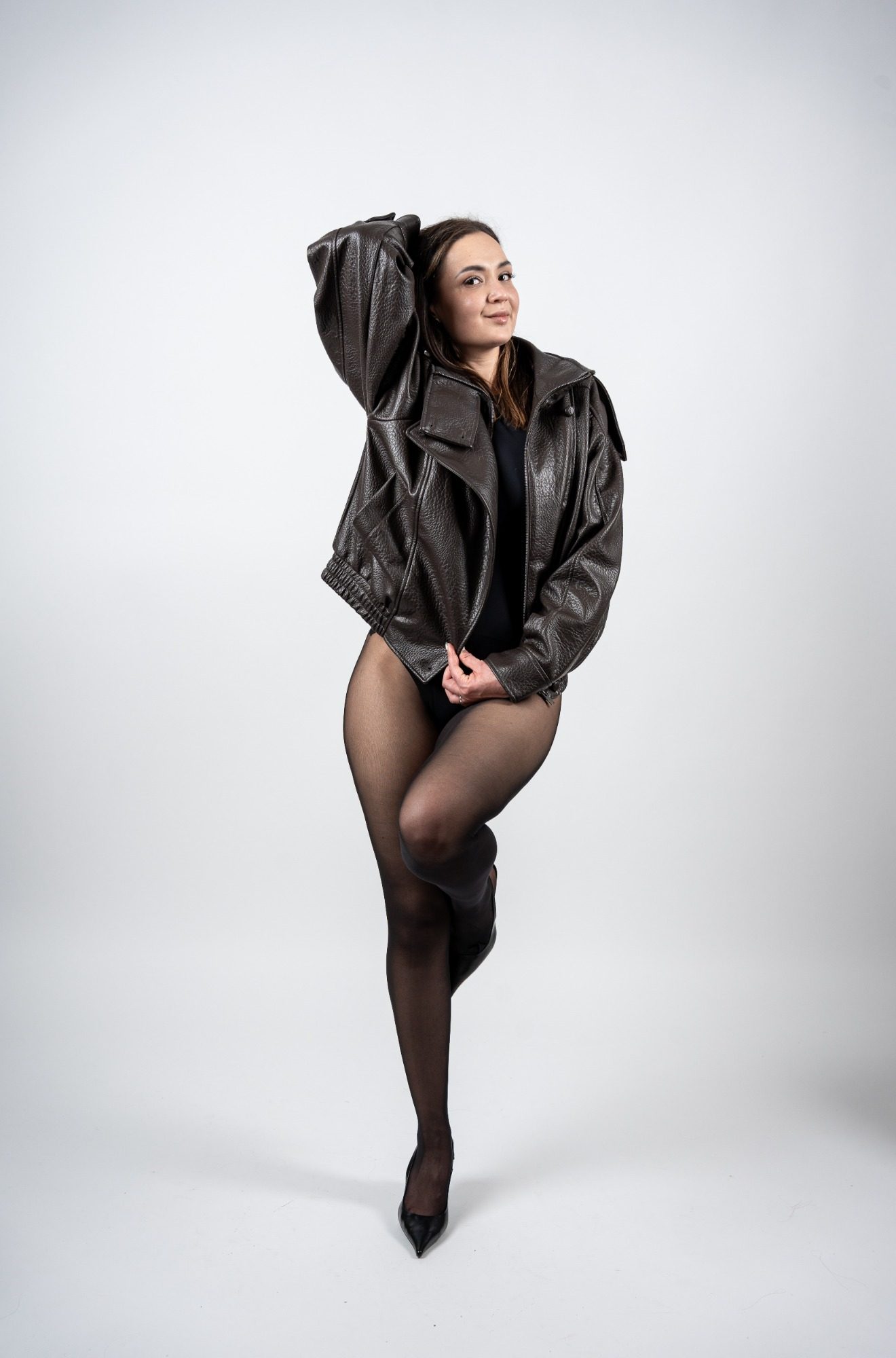 Frau in Lederjacke posiert im Fotostudio vor weißem Hintergrund