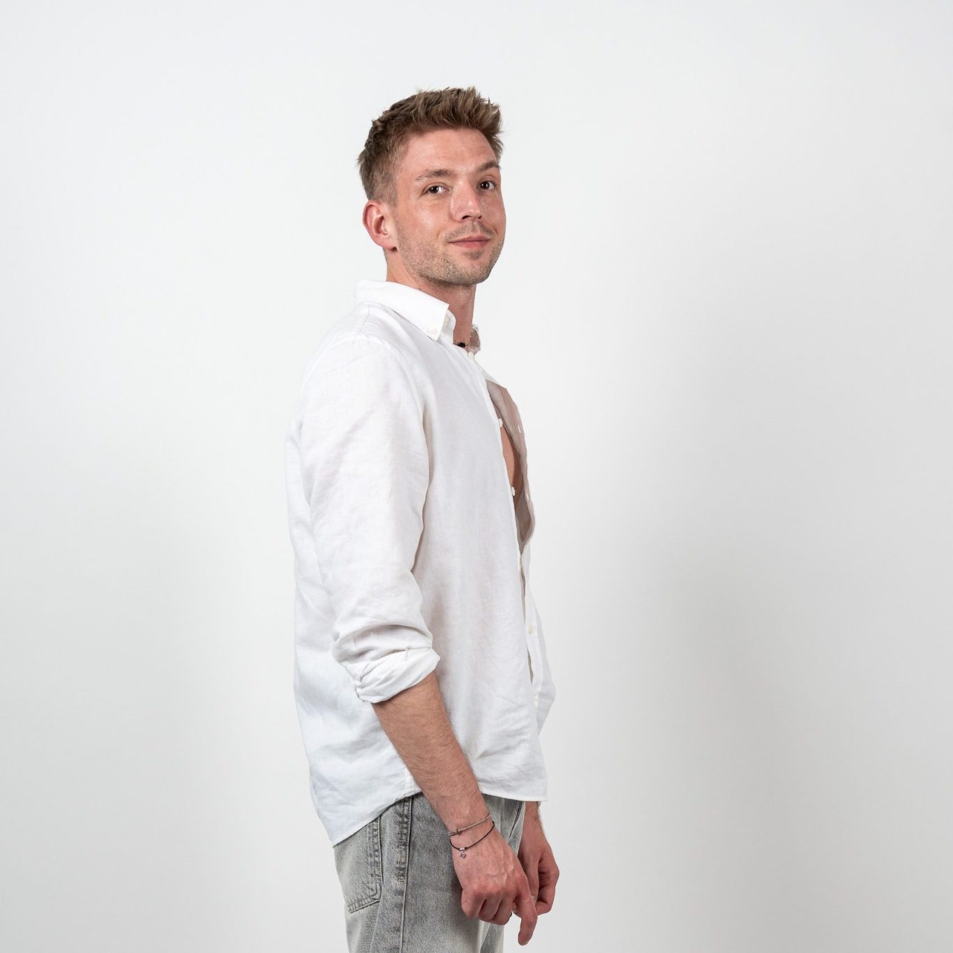 Mann im weißen Hemd vor hellem Studiohintergrund mit direktem Blick in die Kamera.