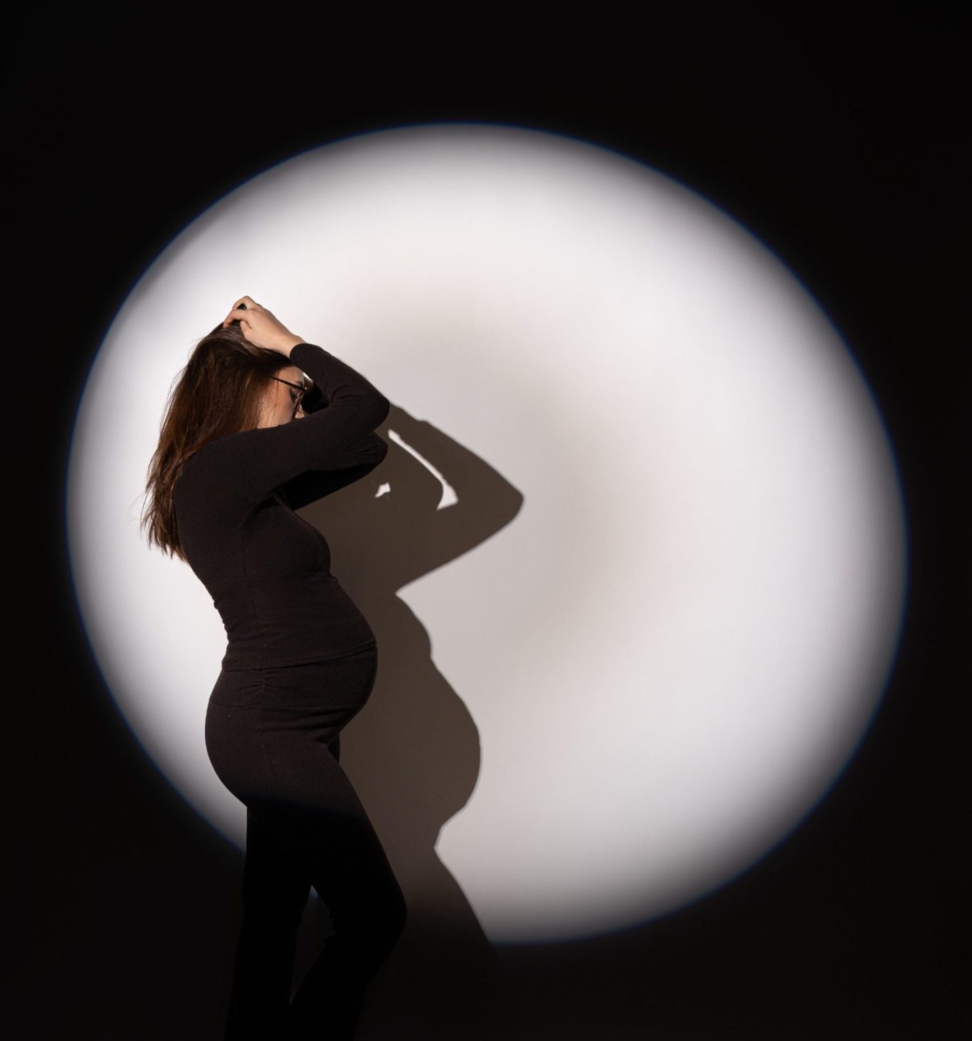 Frau im Spotlight-Licht vor dunklem Hintergrund im Studio